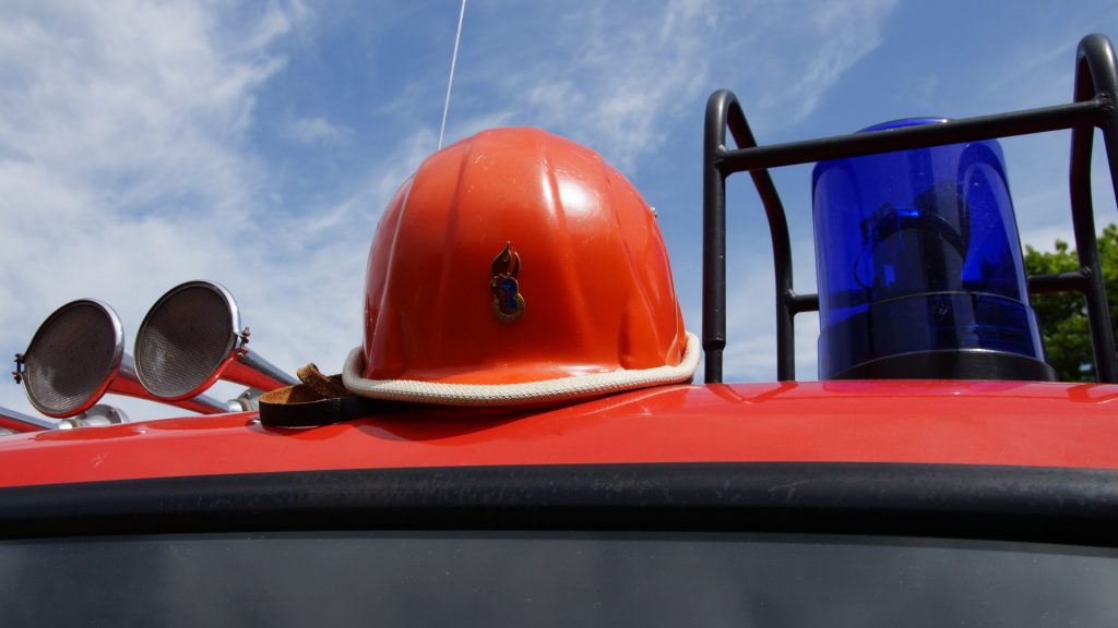 Helm der Deutschen Jugendfeuerwehr auf Feuerwehrauto neben Sirene